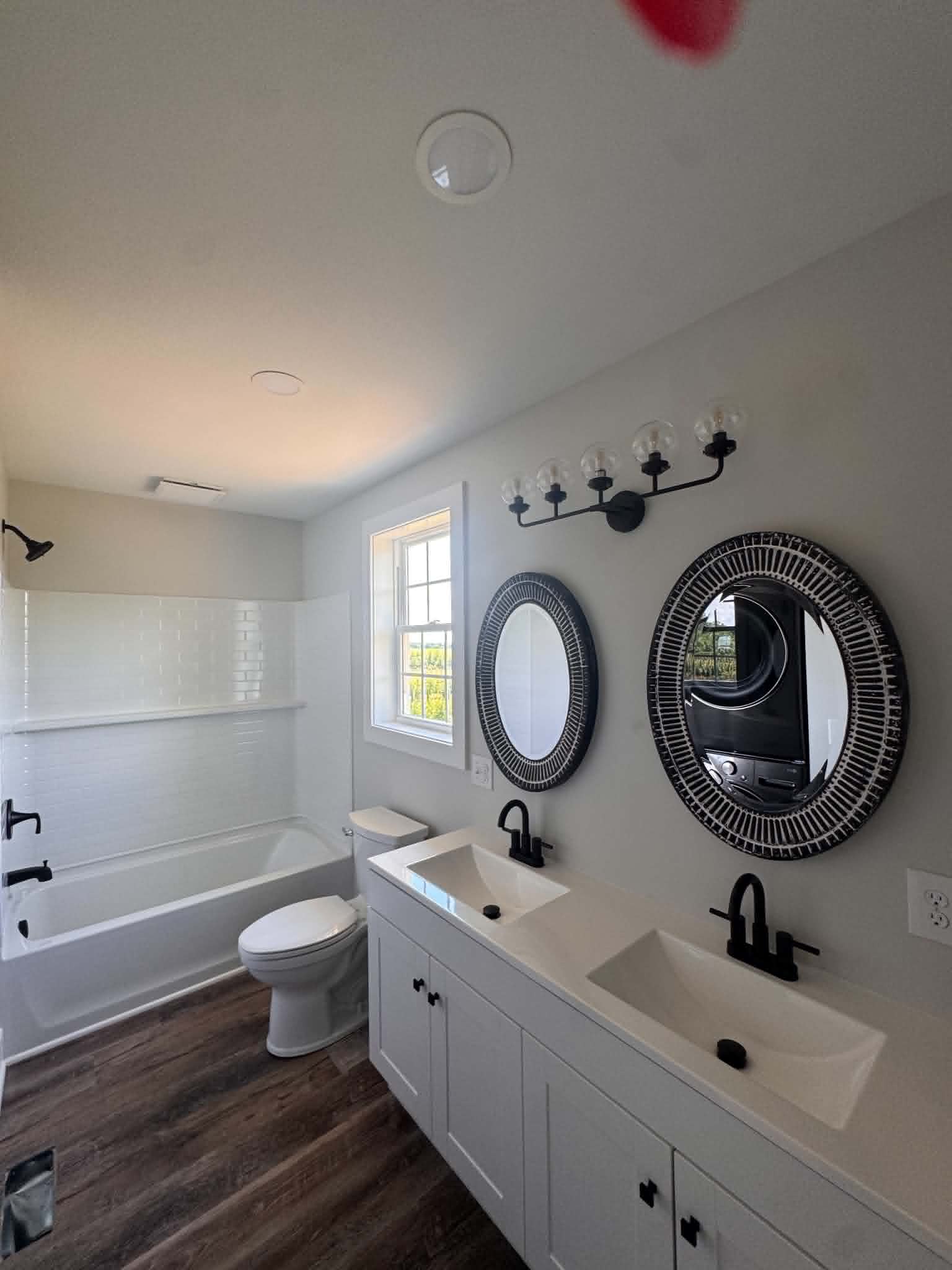 Bathroom renovation with round mirrors and black fixtures